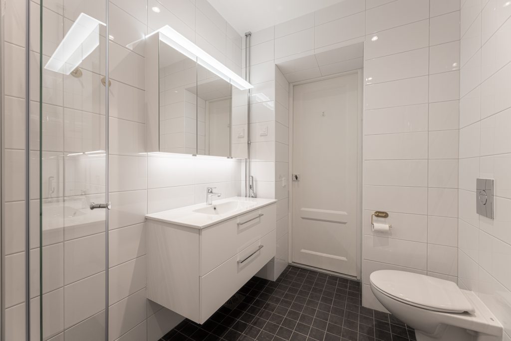 Laajennettu kylpyhuone. Seinä-wc on asennettu aiemman oven tilalle. Valkoisilla pinnoilla ja kalusteilla haluttiin luoda puhdas ja raikas vaikutelma.